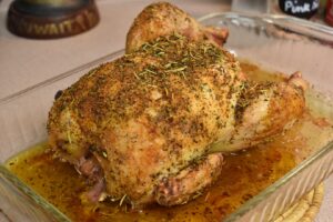 whole chicken with best herb blend on it in a clear glass baking dish