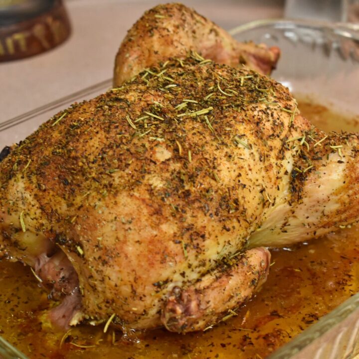 whole chicken with best herb blend on it in a clear glass baking dish