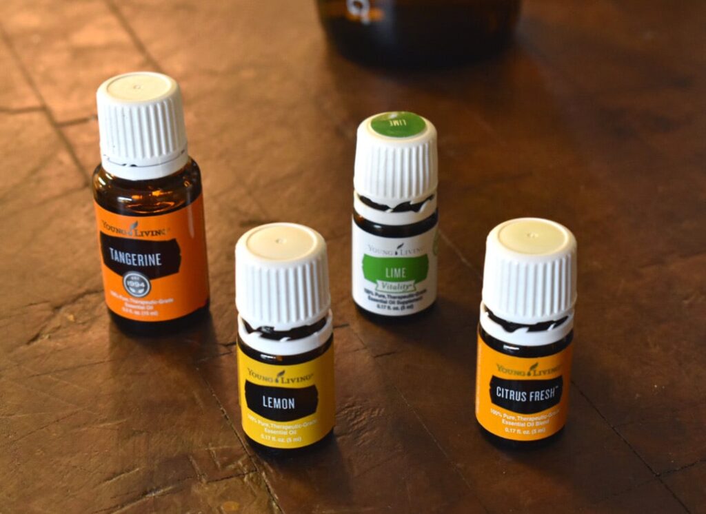 tangerine, lemon, lime, and citrus fresh young living essential oils on a wooden counter