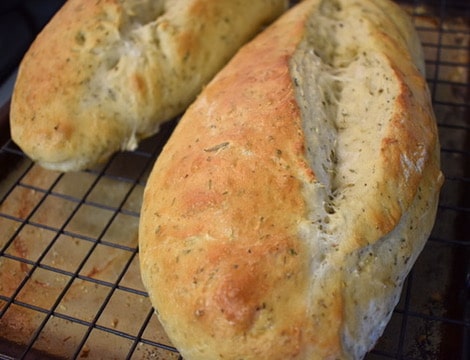 two italian herb bread loaves close up on cooling rack