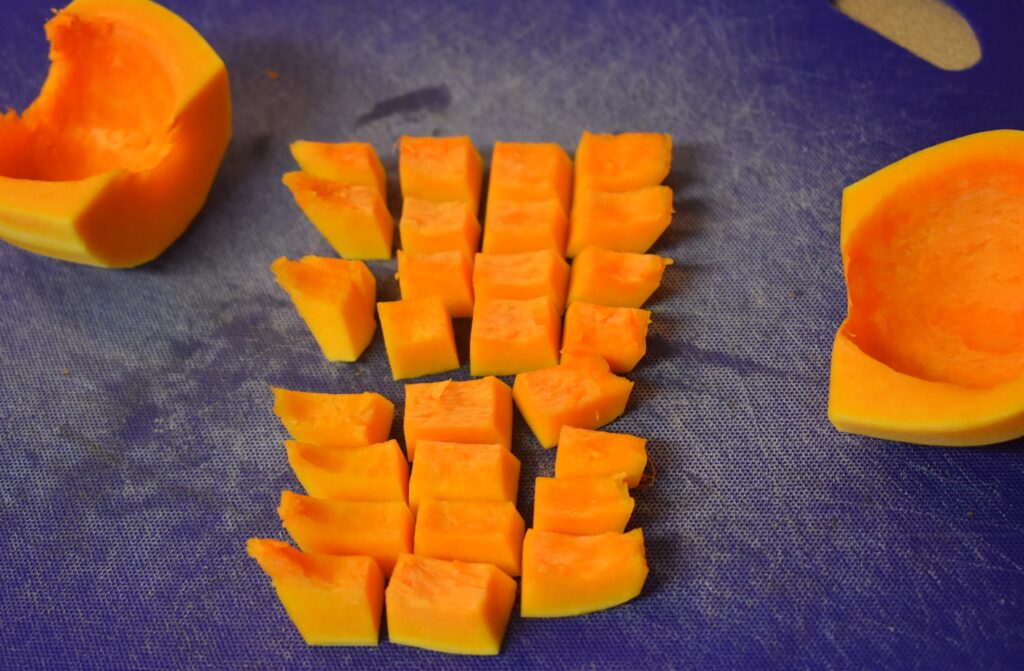 diced seed bellies of butternut squash to roast on blue cutting board