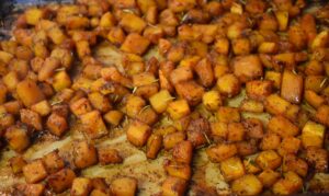 fully roasted maple glazed butternut squash on baking sheet with herbs