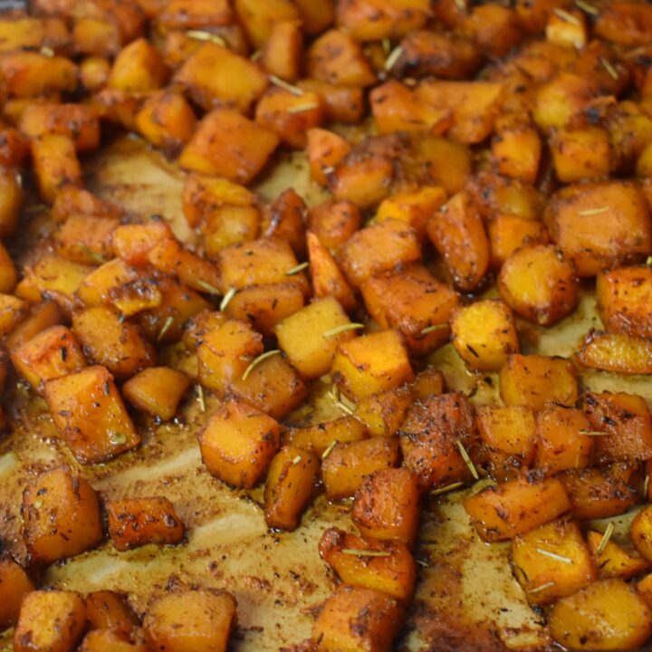 fully roasted maple glazed butternut squash on baking sheet with herbs