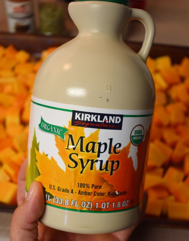 maple syrup jug in front diced butternut squash on roasting tray