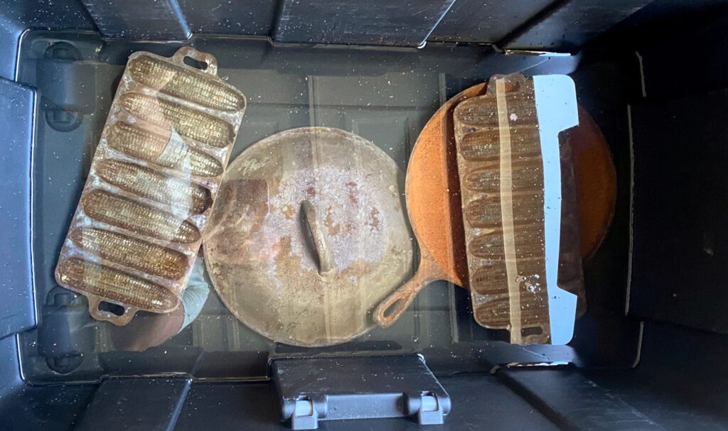 multiple vintage rusty cast iron pieces soaking in vinegar