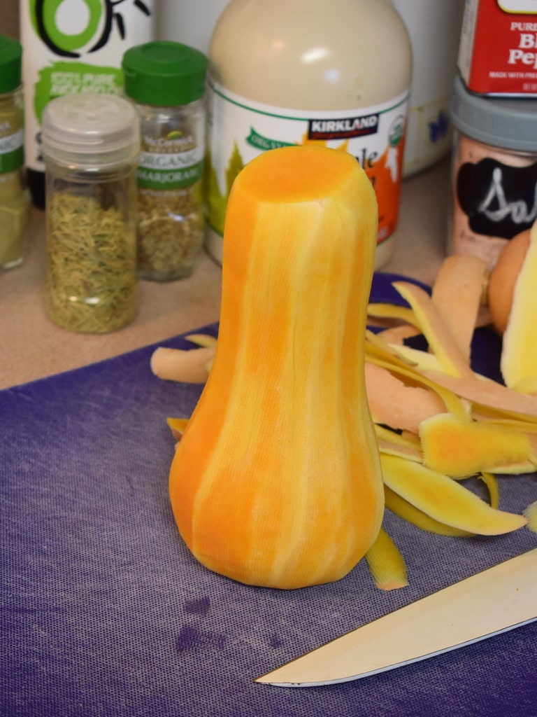 peeled butternut squash standing up on a blue cutting board