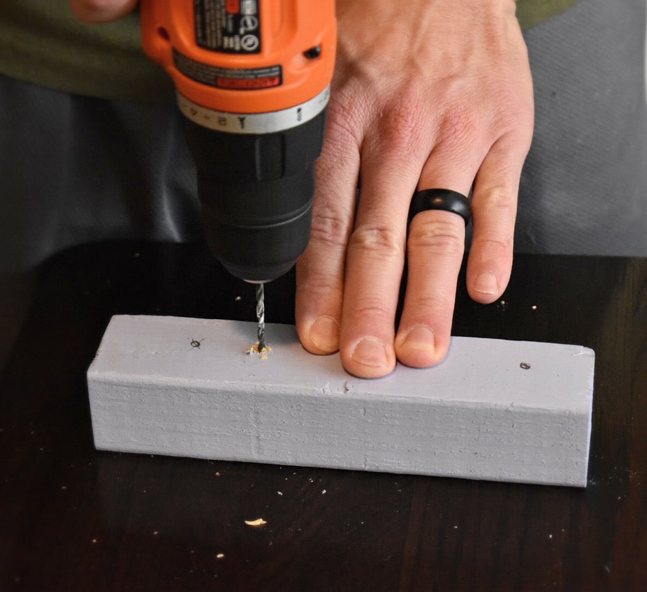 man drilling a hole in a small piece of wood