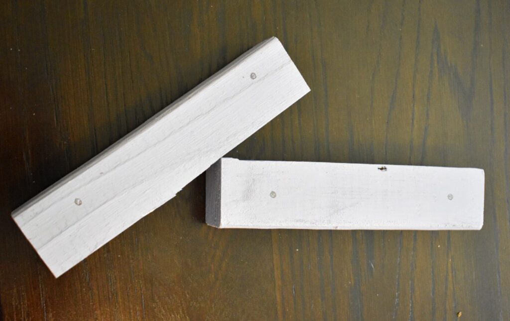 two painted pieces of wood sitting on a brown table