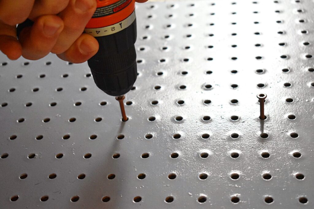 a drill screwing in screws to a peg board
