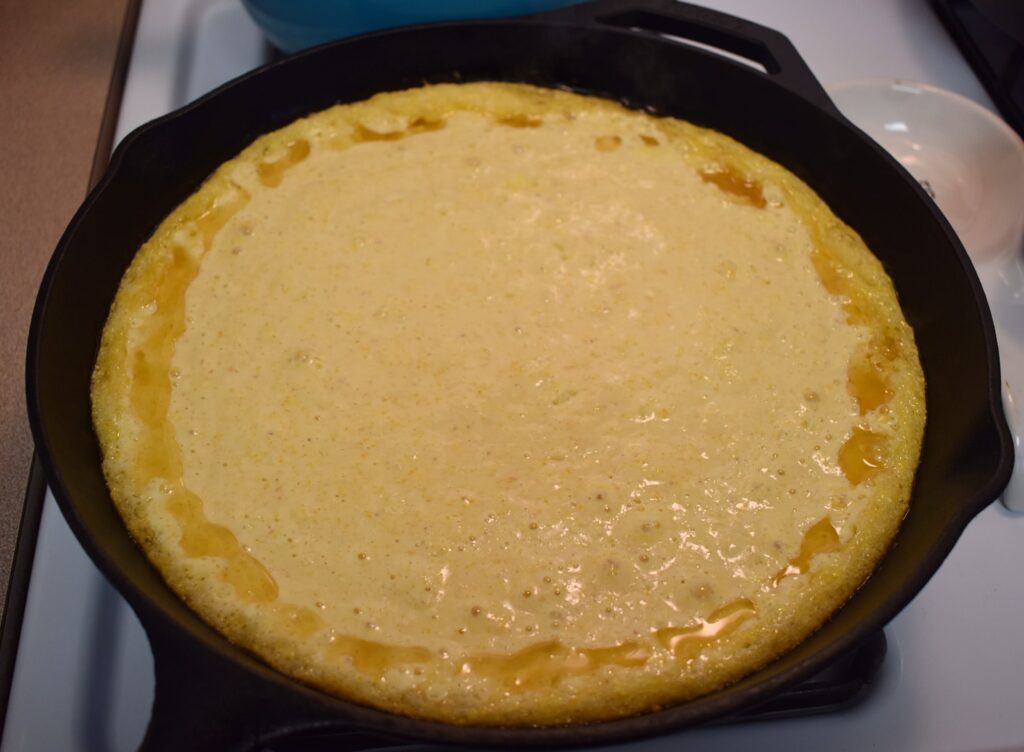 cast iron skillet cornbread batter poured in skillet with hot oil