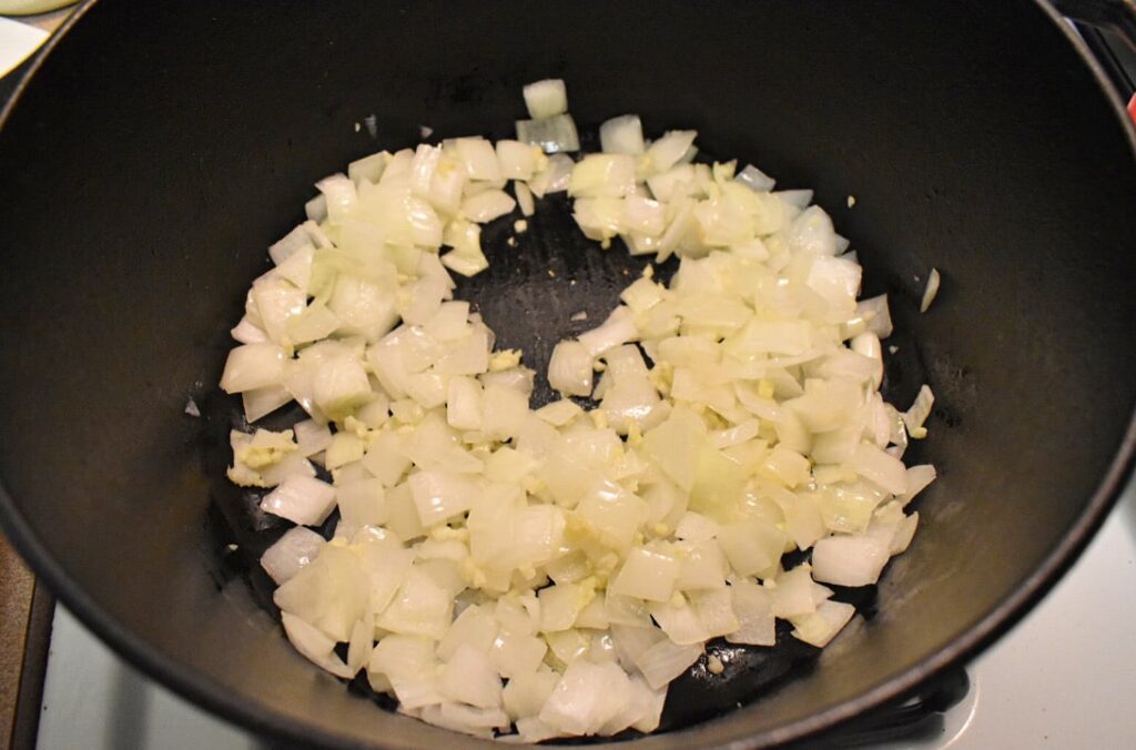 onions and garlic sautéing in cast iron dutch oven