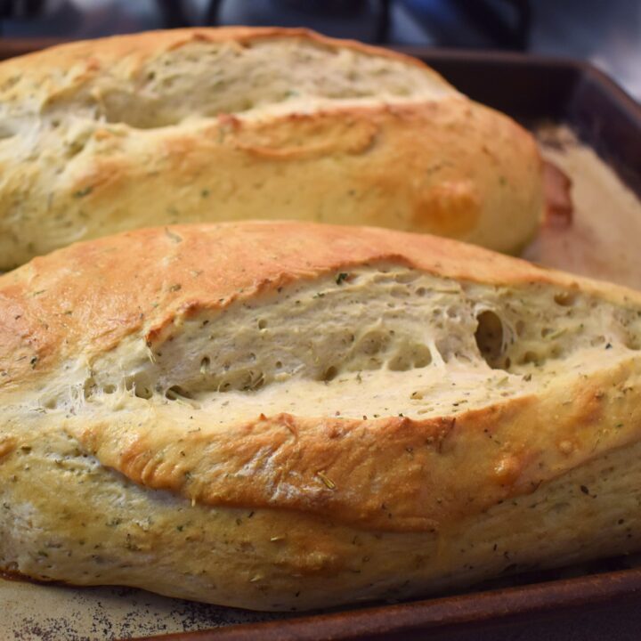two italian herb bread loaves on baking tray after cooking