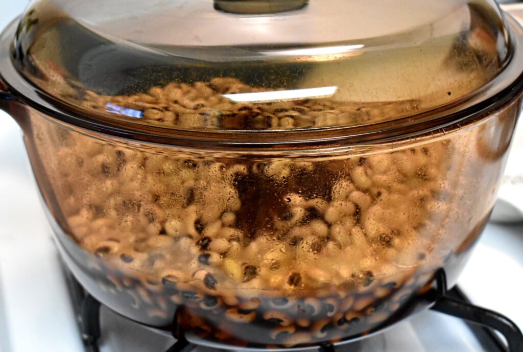 soaked black eyed peas in a pot with a ham bone