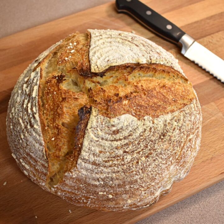 tasty rustic simple sourdough loaf on a wooden cutting board with a bread knife