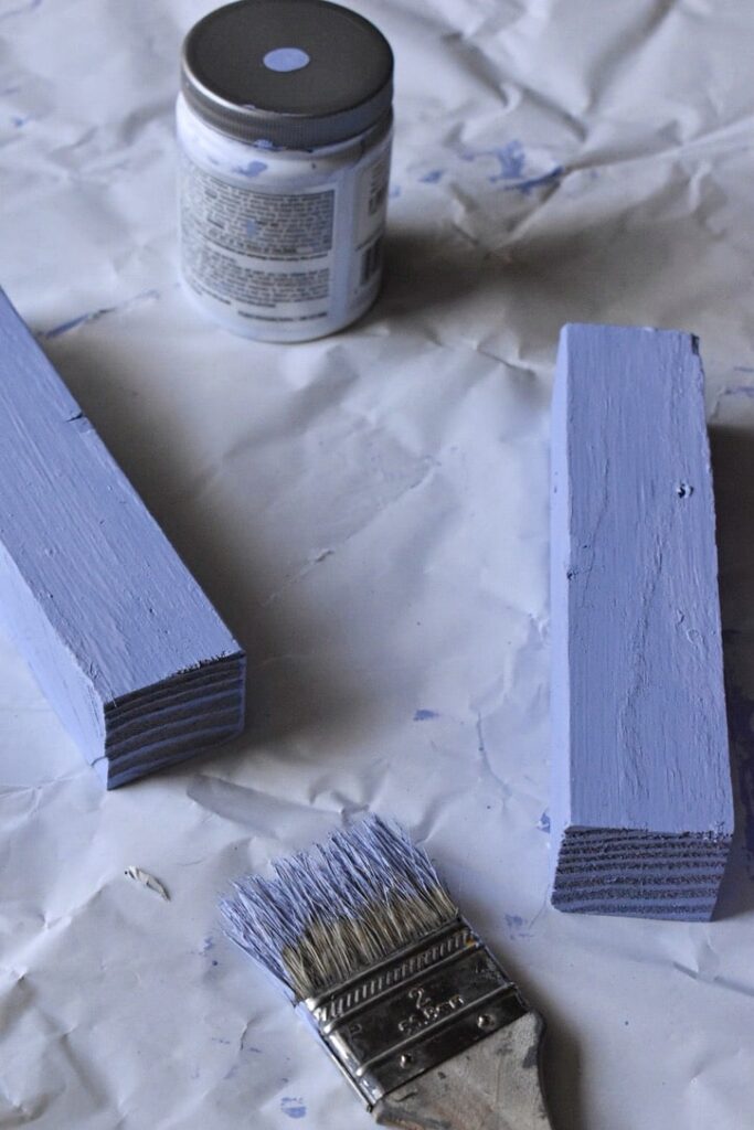 paint sample, two painted pieces of wood and a paint brush